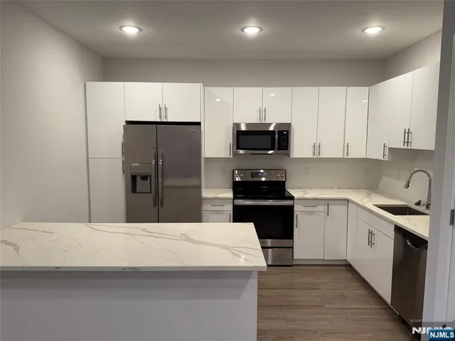 a kitchen with stainless steel appliances a refrigerator sink and white cabinets