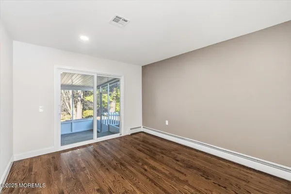 a view of empty room with wooden floor and entryway