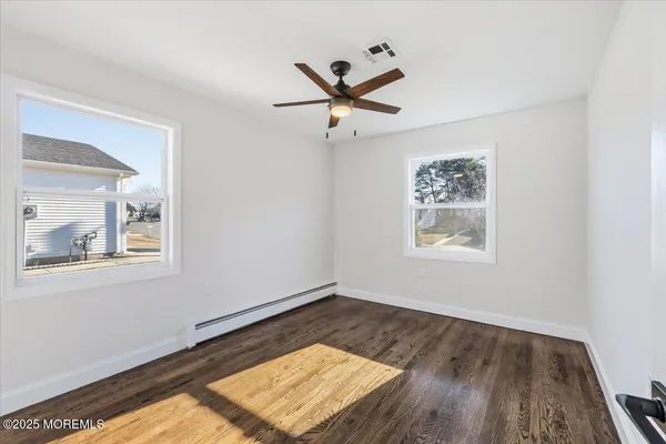 a view of empty room with wooden floor and fan