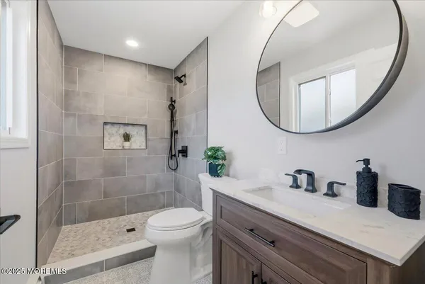 a bathroom with a granite countertop toilet sink and mirror