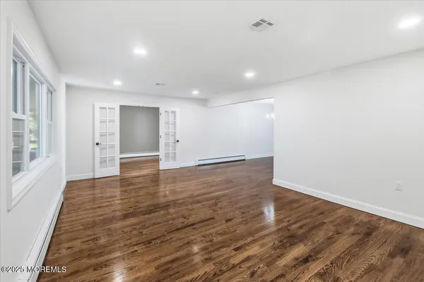 an empty room with wooden floor and windows