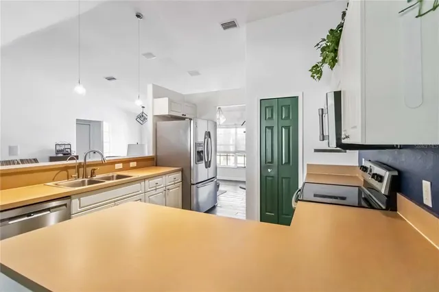 a large white kitchen with stainless steel appliances a large counter top a stove and a refrigerator