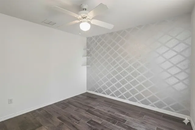 an empty room with wooden floor and fan