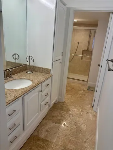 a bathroom with a granite countertop sink a mirror and a shower