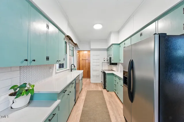 a kitchen with stainless steel appliances granite countertop a refrigerator a sink a stove and a refrigerator