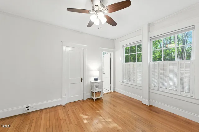 a view of empty room with wooden floor and fan
