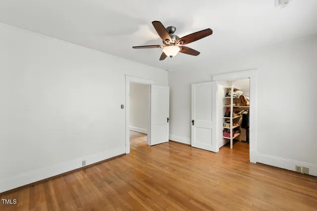 a view of empty room with wooden floor and ceiling fan
