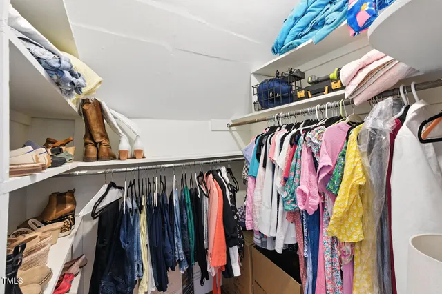 a view of walk in closet with clothes and shoes