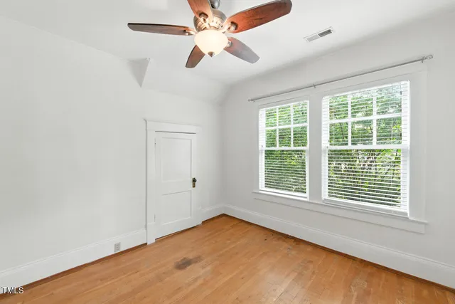 an empty room with ceiling fan and windows