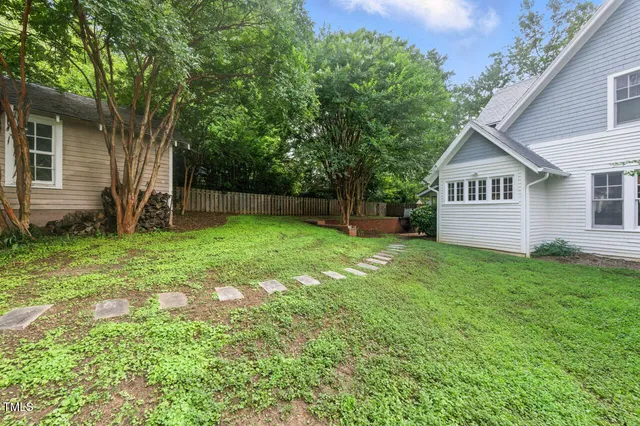 a view of a house with a yard and a large tree