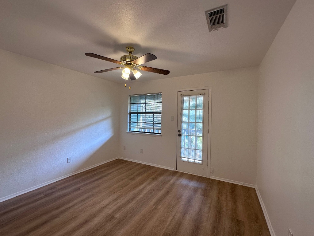 1007 Water Street, Unit 104 Bastrop, TX 78602 - Photo 14 of 23 wooden floor in an empty room with a window