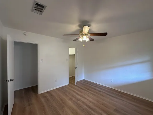 an empty room with wooden floor mirror and window