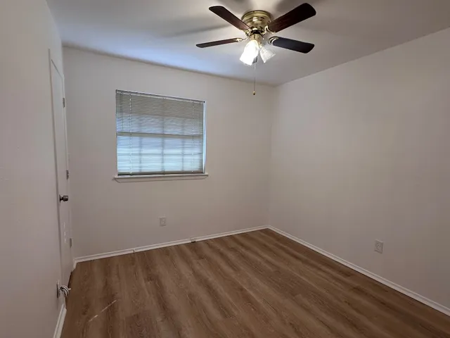 an empty room with a window and a fan
