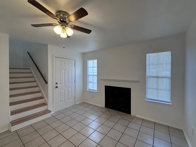 an empty room with windows fireplace and fan