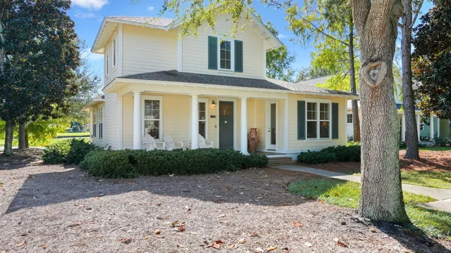 a front view of a house with garden and trees