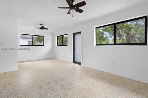 a view of a livingroom with a ceiling fan & windows