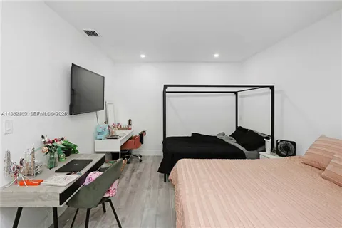 a bedroom with a bed window and table chair
