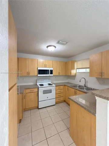a kitchen with a sink a stove top oven and cabinetry