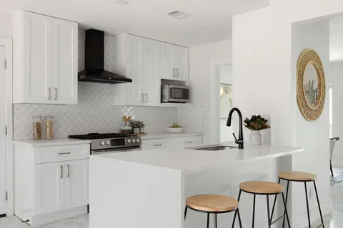 a kitchen with stainless steel appliances a white cabinets and a stove top oven
