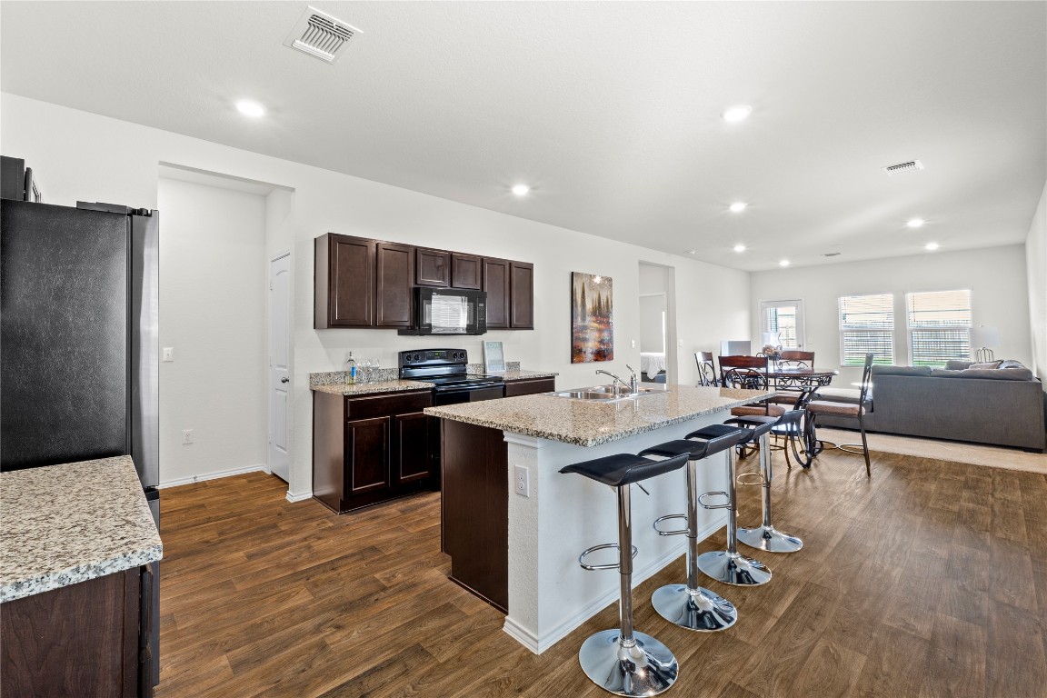14806 Bajada Road Manor, TX 78653 - Photo 4 of 28 a kitchen with stainless steel appliances granite countertop a table chairs sink and cabinets