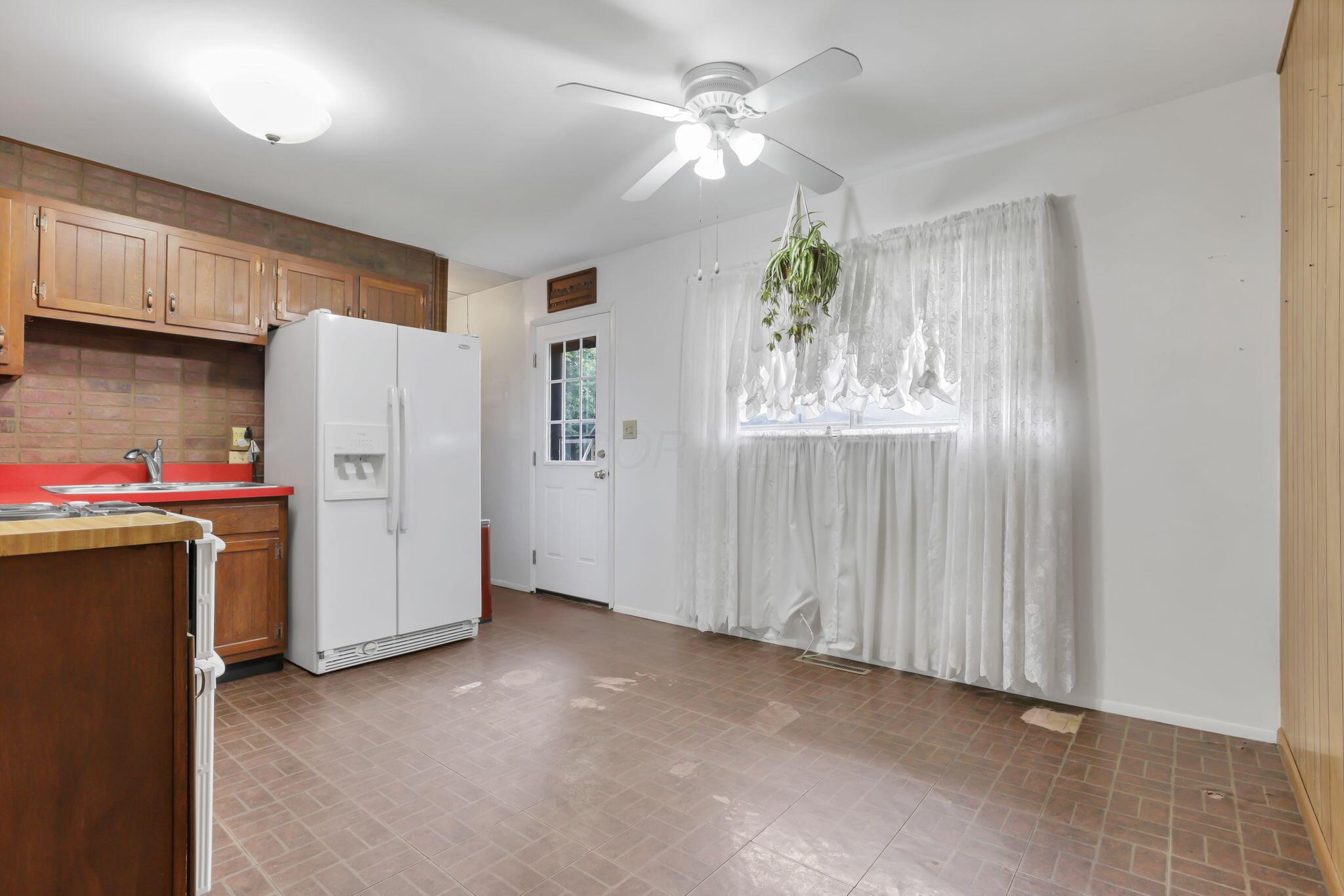 3882 Glenfield Road Columbus, OH 43232 - Photo 10 of 29 Spacious kitchen with a brick backsplash, wood-finish cabinetry, and red countertops