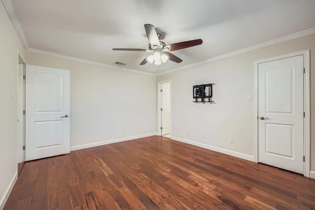 an empty room with wooden floor ceiling fan and window