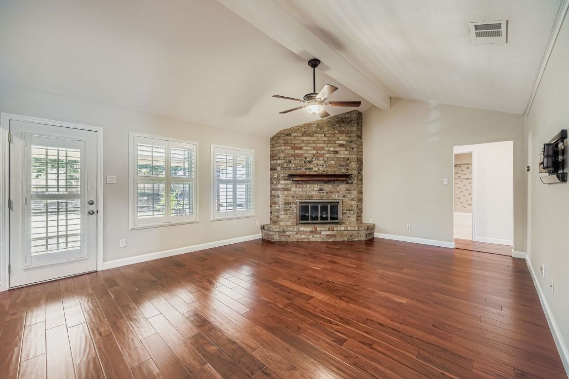 7202 Beckett Road Austin, TX 78749 - Photo 7 of 28 a view of an empty room with wooden floor fireplace and a window