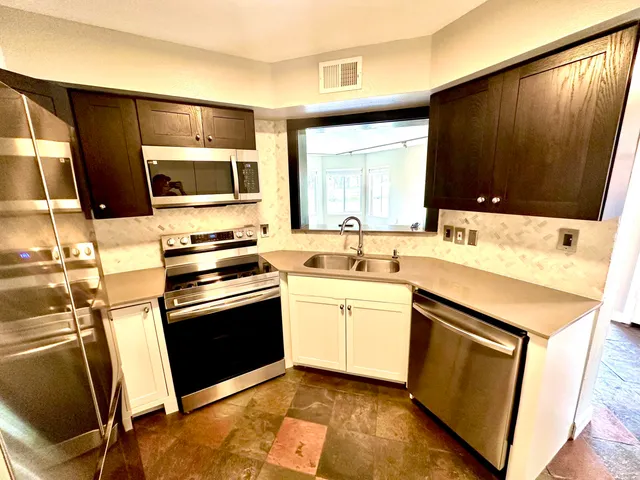 a kitchen with stainless steel appliances kitchen island granite countertop a sink stove and microwave
