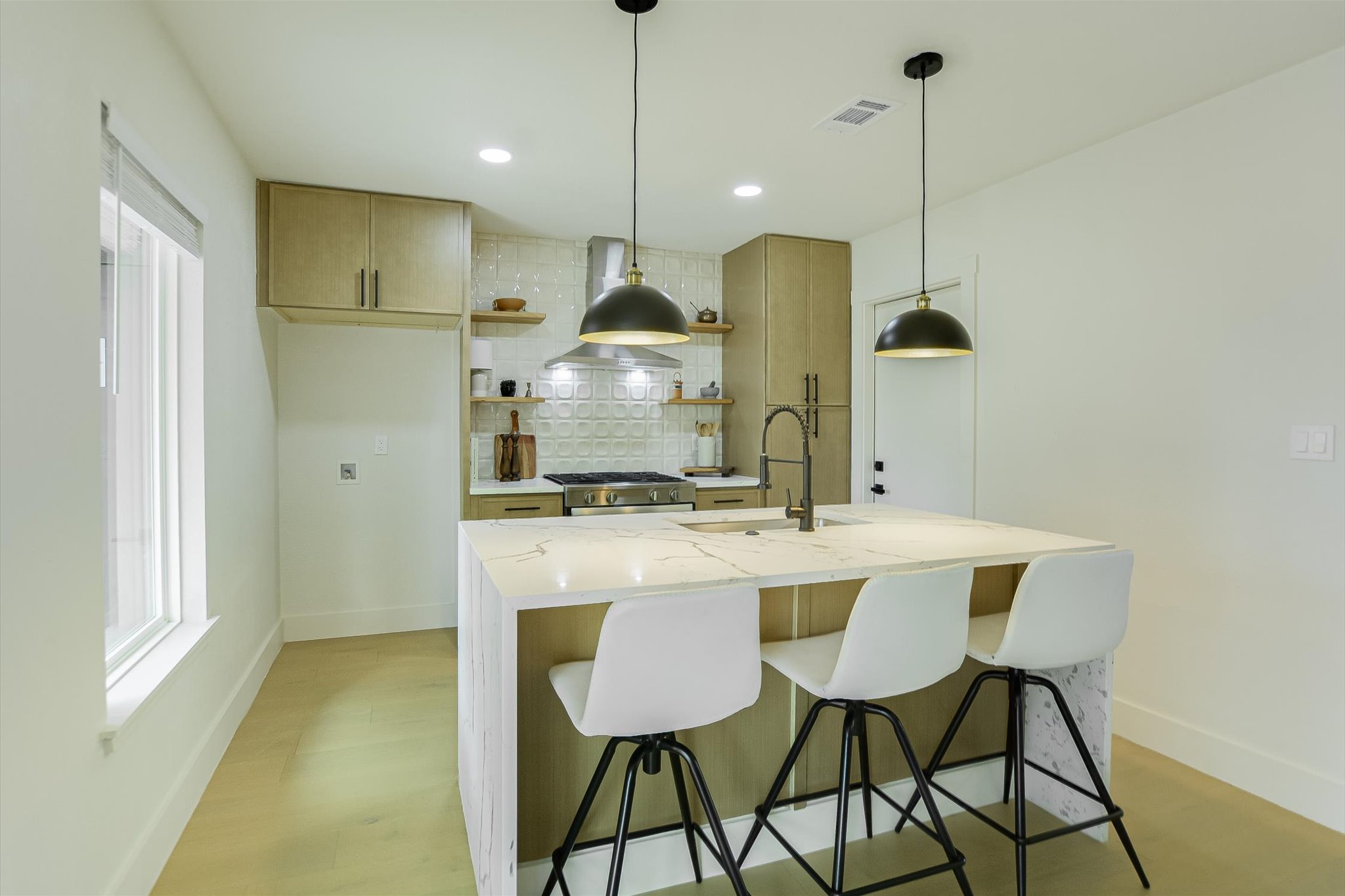 4505 Kitty Avenue Austin, TX 78721 - Photo 3 of 11 A well-lit kitchen with a spacious island, contemporary pendant lighting, and light-toned cabinetry.