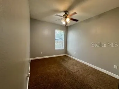 a view of an empty room with a chandelier fan