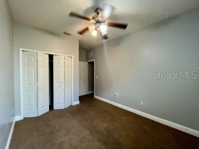 an empty room with a chandelier fan and windows