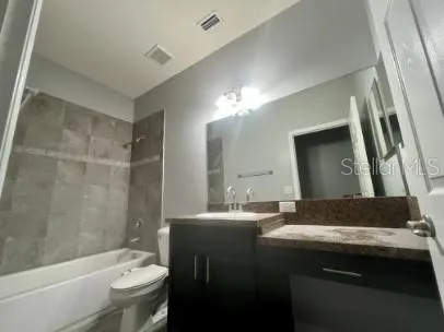 a bathroom with a granite countertop sink a toilet a mirror and shower