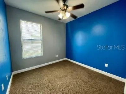 an empty room with a window and a fan