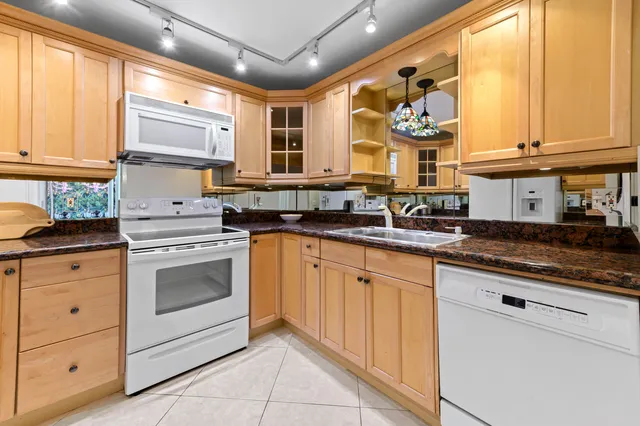 a kitchen with granite countertop white cabinets and white appliances
