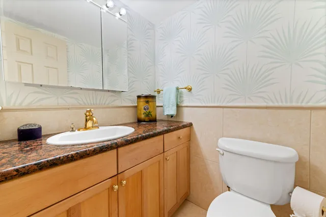 a bathroom with a granite countertop toilet sink and mirror