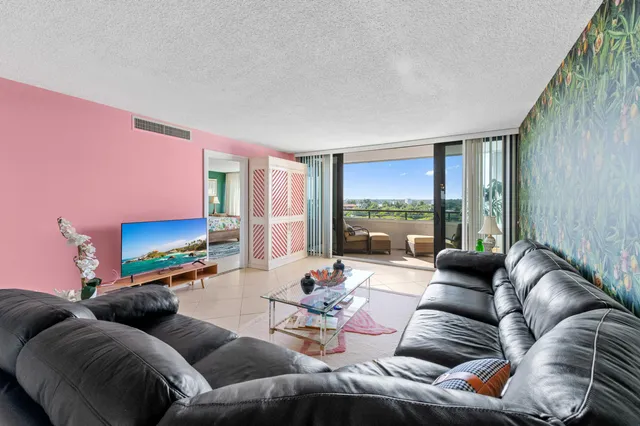 a living room with furniture floor to ceiling window and a flat screen tv