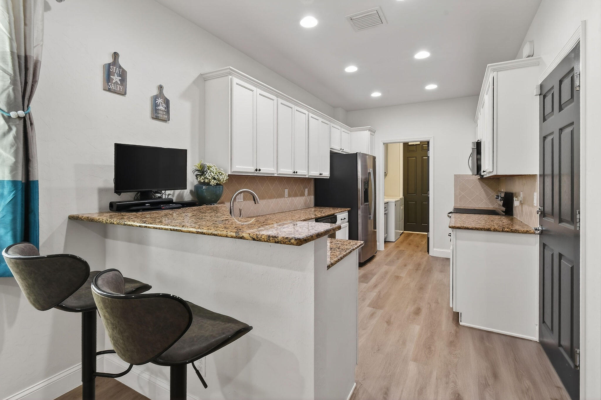 3241 Hemingway Drive Jupiter, FL 33458 - Photo 12 of 39 a kitchen with stainless steel appliances granite countertop a stove top oven a sink a refrigerator white cabinets and wooden floor