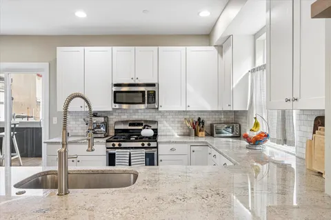 a kitchen with stainless steel appliances granite countertop a sink a stove and a microwave