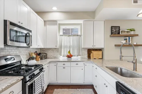 a kitchen with granite countertop a sink a stove and cabinets