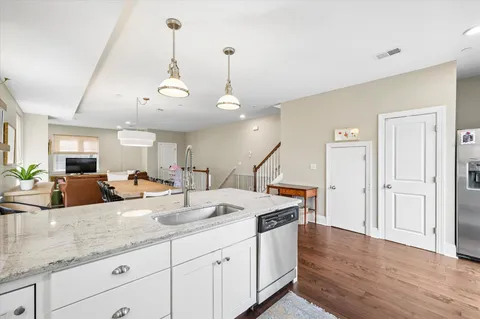 a open kitchen with stainless steel appliances granite countertop a sink a island a stove a refrigerator and white cabinets with wooden floor