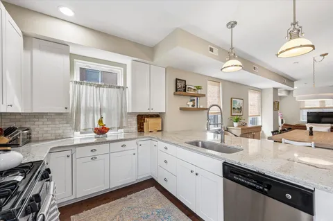 a kitchen with a sink dishwasher and white cabinets with wooden floor