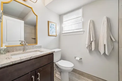 a bathroom with a granite countertop sink a toilet and a mirror