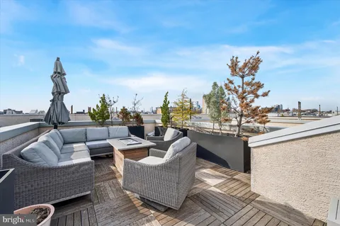 a view of roof deck with couches and potted plants