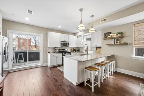a kitchen with stainless steel appliances kitchen island granite countertop a wooden floor and white cabinets
