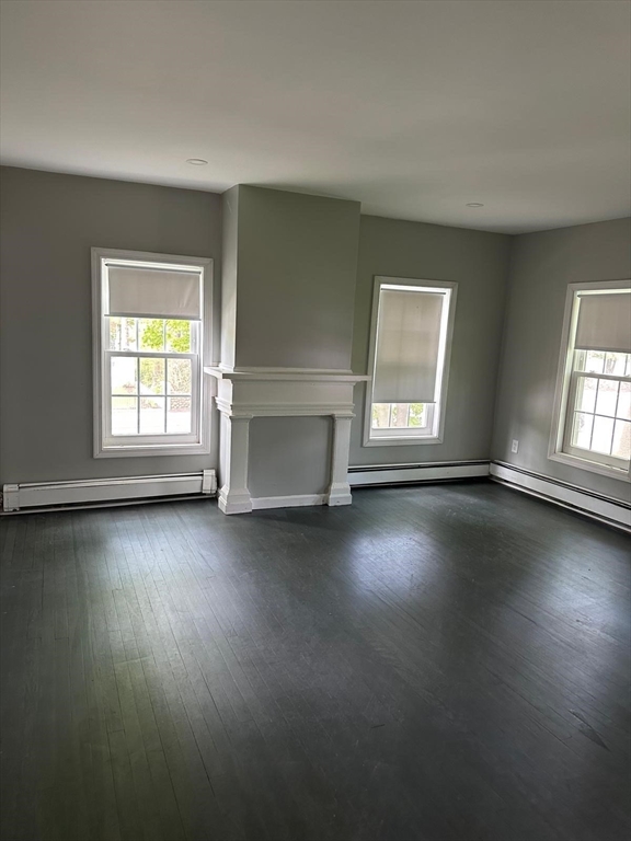 465 North Main Street, Unit 2 Randolph, MA 02368 - Photo 3 of 4 an empty room with wooden floor and windows with curtains