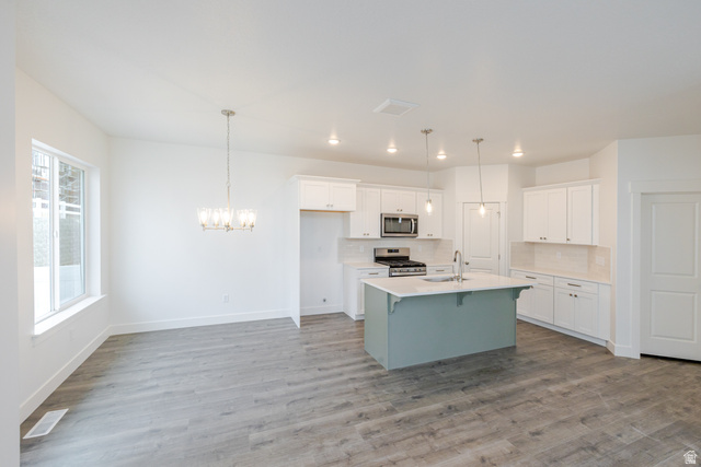 4741 Olive Avenue, Unit 406 Mapleton, UT 84664 - Photo 6 of 20 Dual tone kitchen featuring a kitchen bar, two tone cabinets, a center island with sink, backsplash, and stainless steel appliances