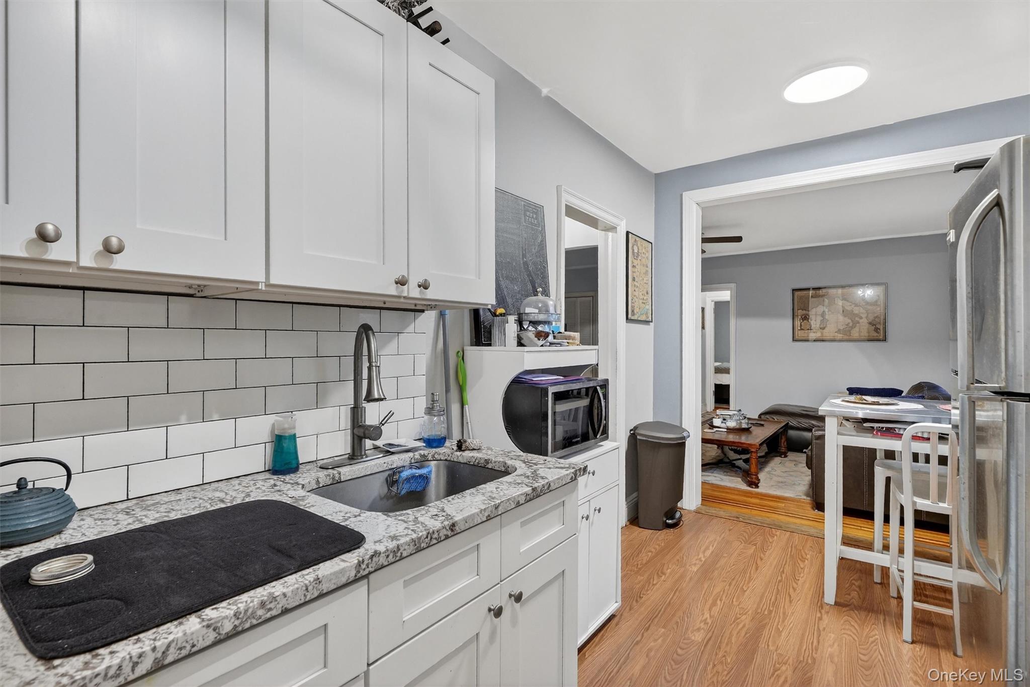 475 Bronx River Road, Unit 2D Yonkers, NY 10704 - Photo 17 of 27 a kitchen with granite countertop a stove a sink a refrigerator and white cabinets with wooden floor