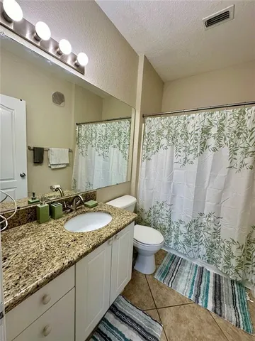 a bathroom with a granite countertop sink a toilet a mirror and shower