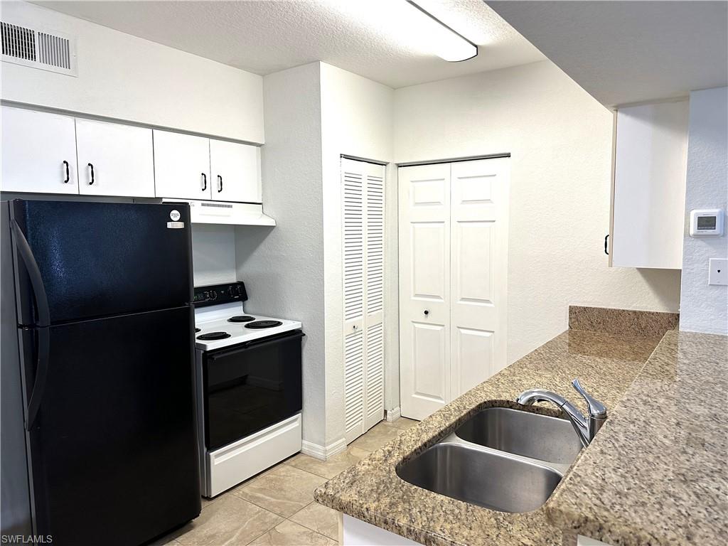 27103 Matheson Avenue, Unit 103 Bonita Springs, FL 34135 - Photo 15 of 29 Kitchen featuring electric stove, black refrigerator, light tile patterned flooring, sink, and white cabinets