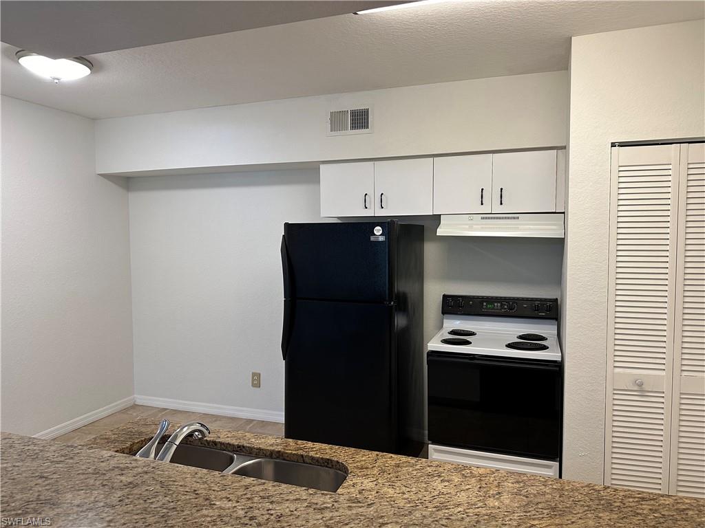 27103 Matheson Avenue, Unit 103 Bonita Springs, FL 34135 - Photo 16 of 29 Kitchen featuring black fridge, white range with electric stovetop, white cabinetry, and sink
